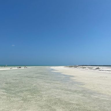 Holbox Plage vaste avec ciel bleu dégagé et mer en arrière-plan.
