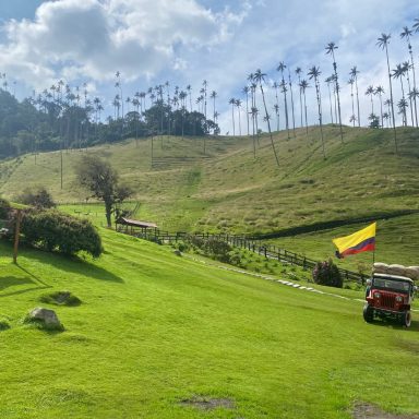Vallée de Cocora, Colombie Paysage verdoyant des Andes avec palmiers, un drapeau colombien et véhicule tout-terrain.