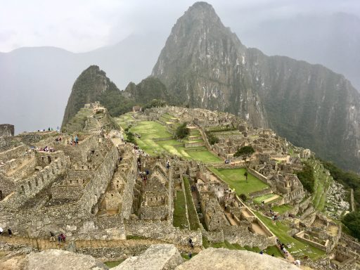 Machu Picchu pérou Ruines de Machu Picchu avec des montagnes en arrière-plan, sous un ciel nuageux.