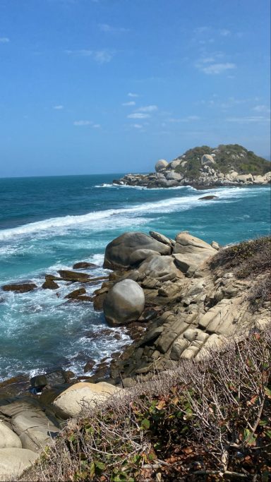 Parc Tayrona, parque tayrona Vue sur une côte rocheuse avec des vagues et une colline à l'arrière-plan.